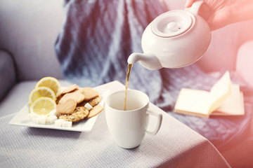 Woman pouring tea in mug from kettle