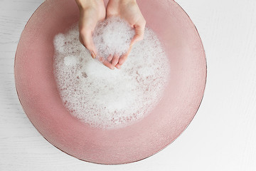 Woman washing hands in bowl isolated on white