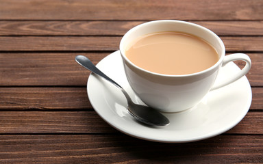 Porcelain cup of tea with milk on wooden background