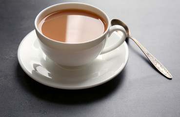 Porcelain cup of tea with milk on gray background