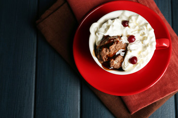 Chocolate mug cake with cream and cranberry on dark wooden background