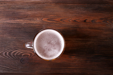 Glass of beer on wooden table, top view