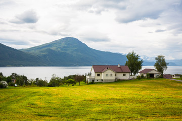 House on the shore against the backdrop of snowy mountains .