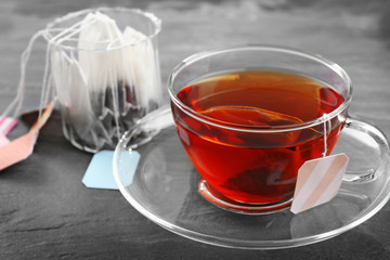 Cup of tea with tea bags on grey background