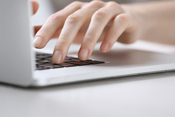 Female hands using laptop on white wooden table, close up