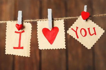 Valentine's Day card with hearts and words of love on wooden background