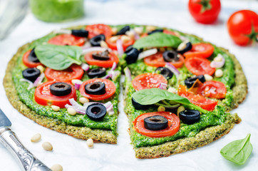 vegan broccoli zucchini pizza crust with spinach pesto, tomatoes