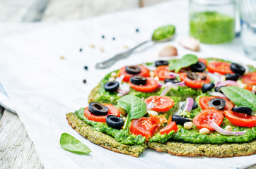 vegan broccoli zucchini pizza crust with spinach pesto, tomatoes