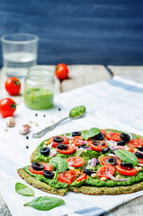 Fototapeta na wymiar vegan broccoli zucchini pizza crust with spinach pesto, tomatoes