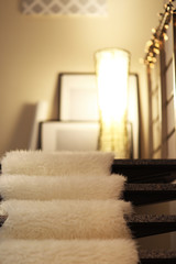 Modern stairs with electric garland, white furry bedspread and lamp