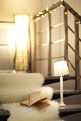 Resting-place with electric garland, book and lamps on modern stairs