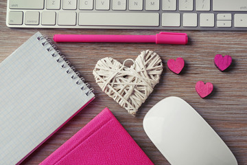 Fototapeta premium Computer peripherals with hearts, pen and notebooks on wooden table