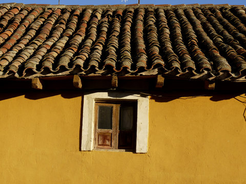 Tejado y ventanuco de una casa amarilla