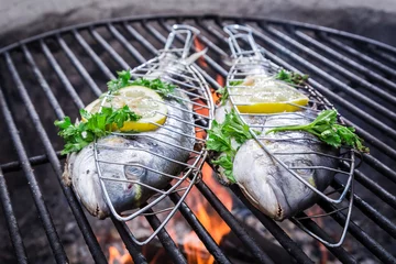 Wall murals Grill / Barbecue Tasty fish with herbs and lemon on grill