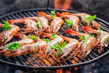 Poster Grill / Barbecue Grilling big prawns with lemon and parsley