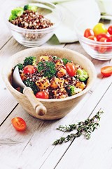 Quinoa salad with broccoli,sweet potatoes and tomatoes on a rustic wooden table.Superfoods concept.Selective focus.
