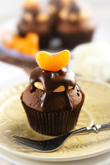 Tasty cupcake with slice of mandarin and chocolate on a plate, close up