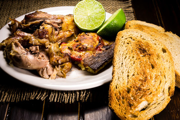 Roasted pork meat, limes and scrambled eggs with red papers and slices of bread 