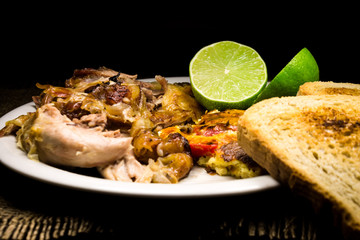 Roasted pork meat, limes and scrambled eggs with red papers and slices of bread 