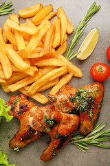 Baked chicken wings with spices and French fries on grey background