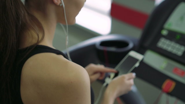 Close-up of a girl with headphones on a treadmill. 4k