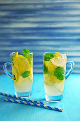 Lemonade with lemon and mint on blue table against blue jalousie
