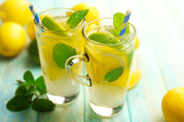 Composition of lemonades,  lemons and mint on blue wooden table background