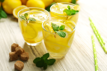 Composition of lemonades with lemons and mint on white wooden table background, closeup