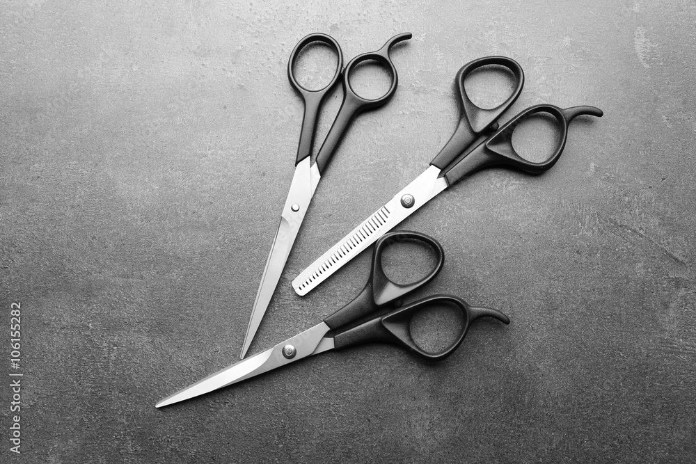 Wall mural Professional metal scissors lying close to each other on a dark grey surface, top view