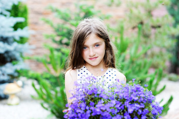 Fototapeta premium Adorable smiling kid girl with flowers