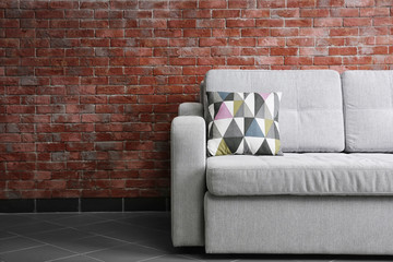 Grey sofa against brick wall in the room