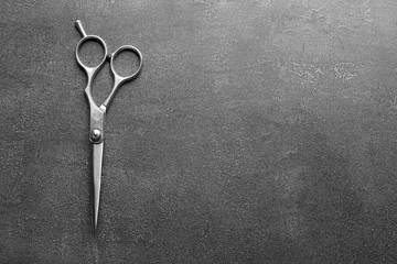 Professional metal scissors on a dark grey surface, top view