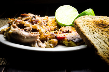 Roasted pork meat, limes and scrambled eggs with red papers and slices of bread 