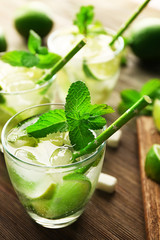 Mojito drink with lime and mint on wooden table