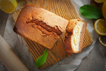 Composition of tasty cake with lemon on cutting board top view, closeup