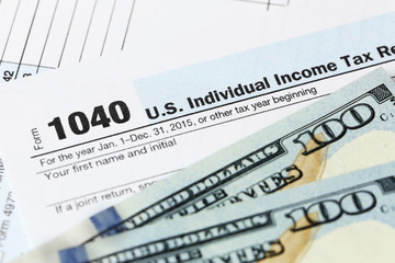Obraz premium 1040 Individual Income Tax Return Form with one hundred dollar bills, close up