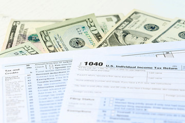 Obraz premium 1040 Individual Income Tax Return Form with dollar bills on white background, close up