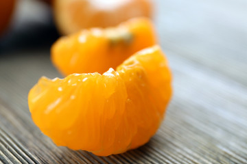 Fresh delicious unpeeled tangerines with slices on the wooden table, close up