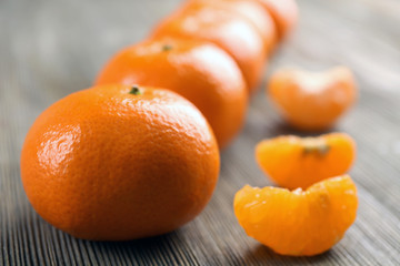 Fresh delicious unpeeled tangerines  with slices lined on the wooden table, close up