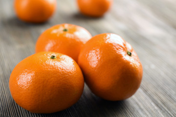 Fresh delicious unpeeled tangerines  in a heap on the wooden table, close up