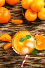 Tangerine cocktail with sliced mandarins, ice, mint on a striped surface, top view