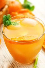 Tangerine cocktail with ice, and mint on a wooden table, close up