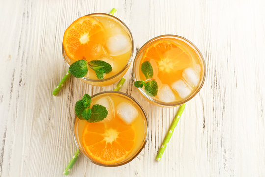 Tangerine cocktails with ice and mint, on a wooden table, top view