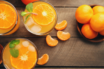Tangerine cocktails with ice and mint on a wooden board, top view