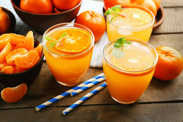 Tangerine cocktails with ice and mint on a wooden table, close up