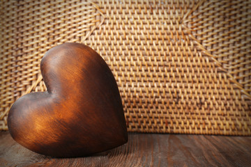 Wooden heart on wicker background, close up