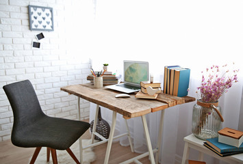 Workplace with laptop, table and chair beside the window