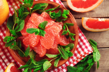 Juicy grapefruit pieces with fresh mint on a plate, close up