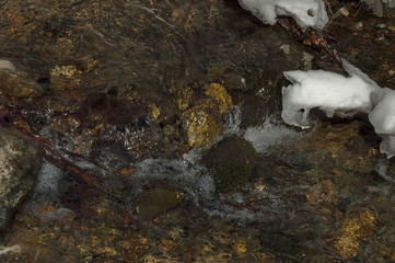 Sunlit hurry mountain stream with melt snow, Vitosha mountain, Bulgaria 