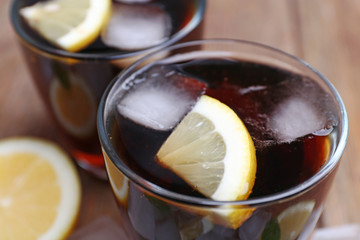 Two glasses of cola with cubes of ice and lemon, closeup
